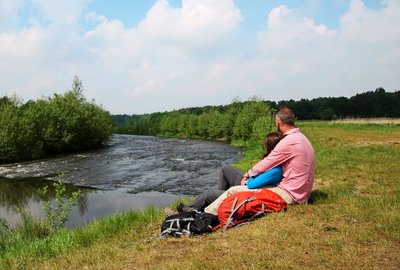 Ein Paar sitzt am Ufer der Wümme und macht Pause bei einer Wanderung