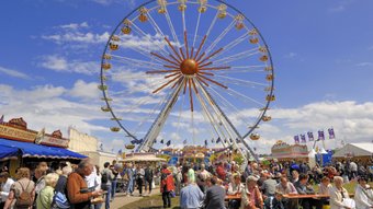 Auf der gut besuchten Tarmstedter Ausstellung steht das Riesenrad hinter Ständen mit Gastronomie 