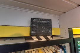 Auf einem Regal steht eine Tafel, wie sie beim Film verwendet wird, mit der Aufschrift des Films "Tadellöser und Wolff"