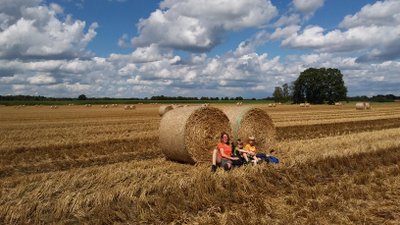 Eine Mutter sitzt auf einem Feld mit ihren beiden Söhnen vor zwei Strohballen