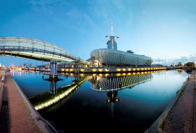 Das Klimahaus 8° Ost in Bremerhaven am Abend mit der beleuchteten Glasbrücke