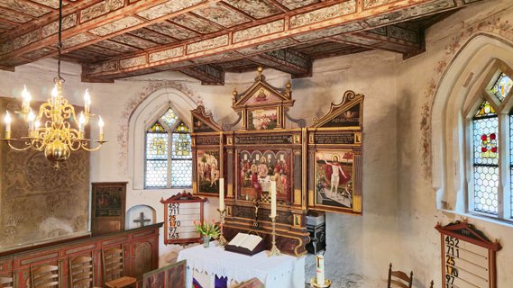 Seitlicher Blick auf den Altar mit dem aufgeklappten Altarbild, einem Triptychon