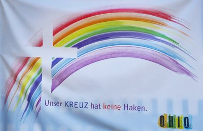 Banner mit einem Kreuz im bunten Regenbogen und der Schrift "Unser Kreuz hat keinen Haken"