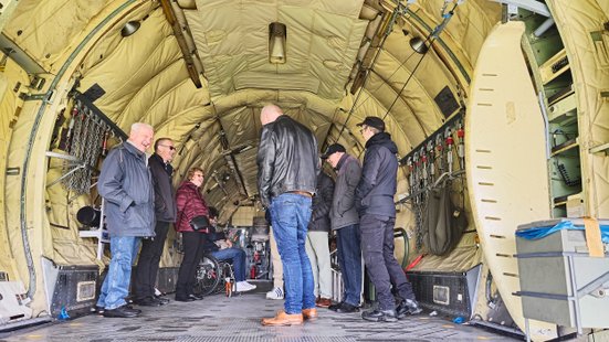 Blick vom Heck in der Transall, dort lässt sich eine Gruppe lachend Wissenswertes vom Guide erzählen