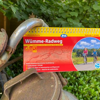 Eine Fahrradkarte vom Wümme-Radweg klemmt an einem verrosteten Deko-Fahrrad