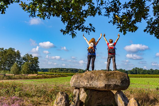 Zwei weibliche Wanderer stehen auf dem Großsteingrab Steinalkenheide und schauen in die Ferne