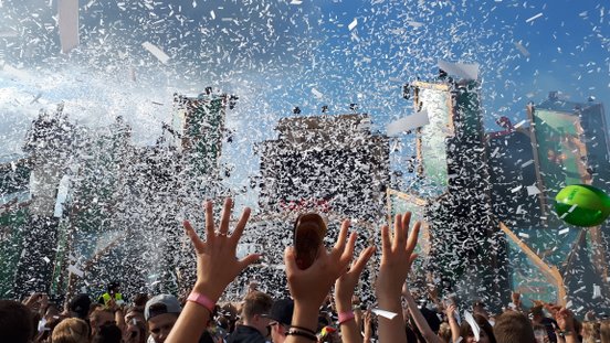 Besucher strecken die Hände hoch im Konfittiregen auf dem Elektropop-Festival Ferdinands Feld