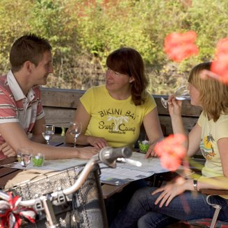 Drei Radler machen eine Pause in einem Café-Garten mitten im Grünen und planen die Weiterfahrt