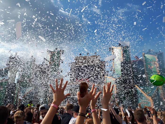 Besucher strecken die Hände hoch im Konfittiregen auf dem Elektropop-Festival Ferdinands Feld