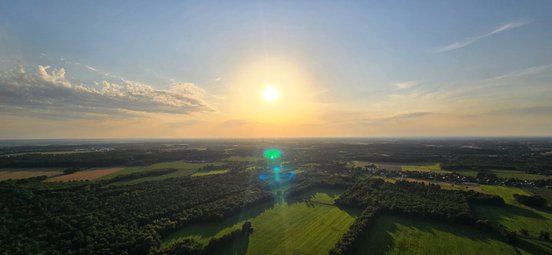 Die orange Abendsonne taucht die weite Landschaft in ein warmes Licht