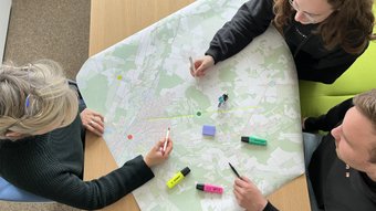 Drei Personen arbeiten mit bunten Stiften an einer Radkarte