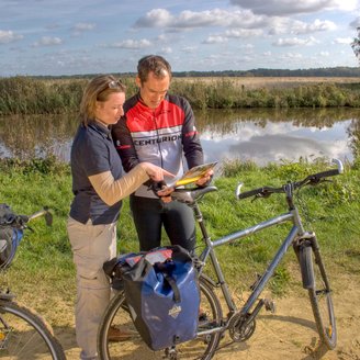 Zwei Radfahrer orientieren sich mit einer Karte in der Hand an der Wümme bei Ritterhude