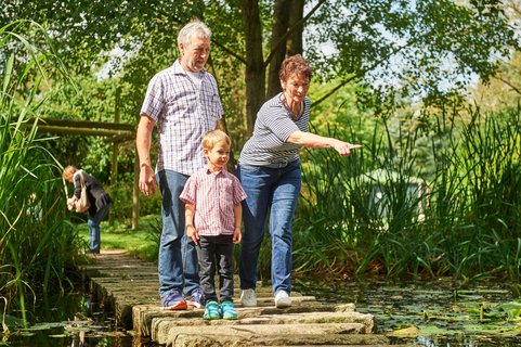 Großeltern zeigen einem Enkelkind etwas im Feuchtbiotop in der Welt der Sinne