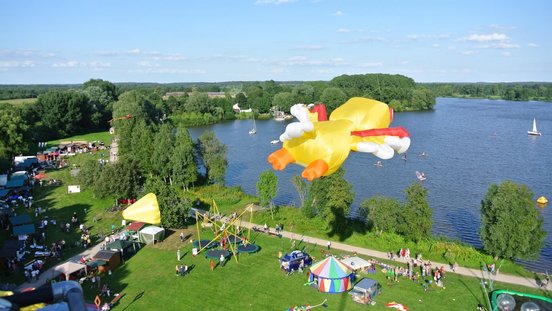 Blick von oben auf das Vörder Seefest mit einem gelben Drachen