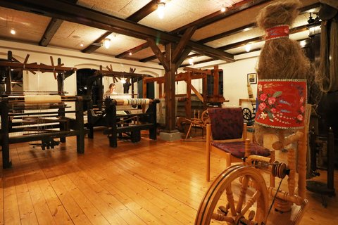 Spinnrad vor Webstühlen