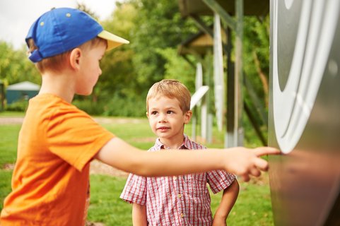 Ein läterer Junge zeigt einem jüngeren ein Rad zum Drehen in der Welt der Sinne