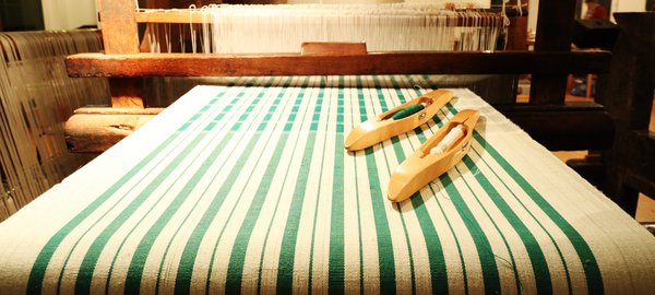 Webstuhl mit grün-weißem Garn und Schiffchen